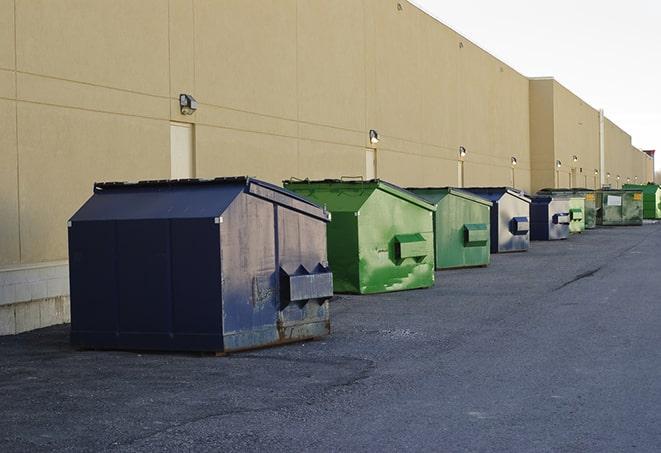 a construction worker empties a wheelbarrow of waste into the dumpster in Royal Palm Beach